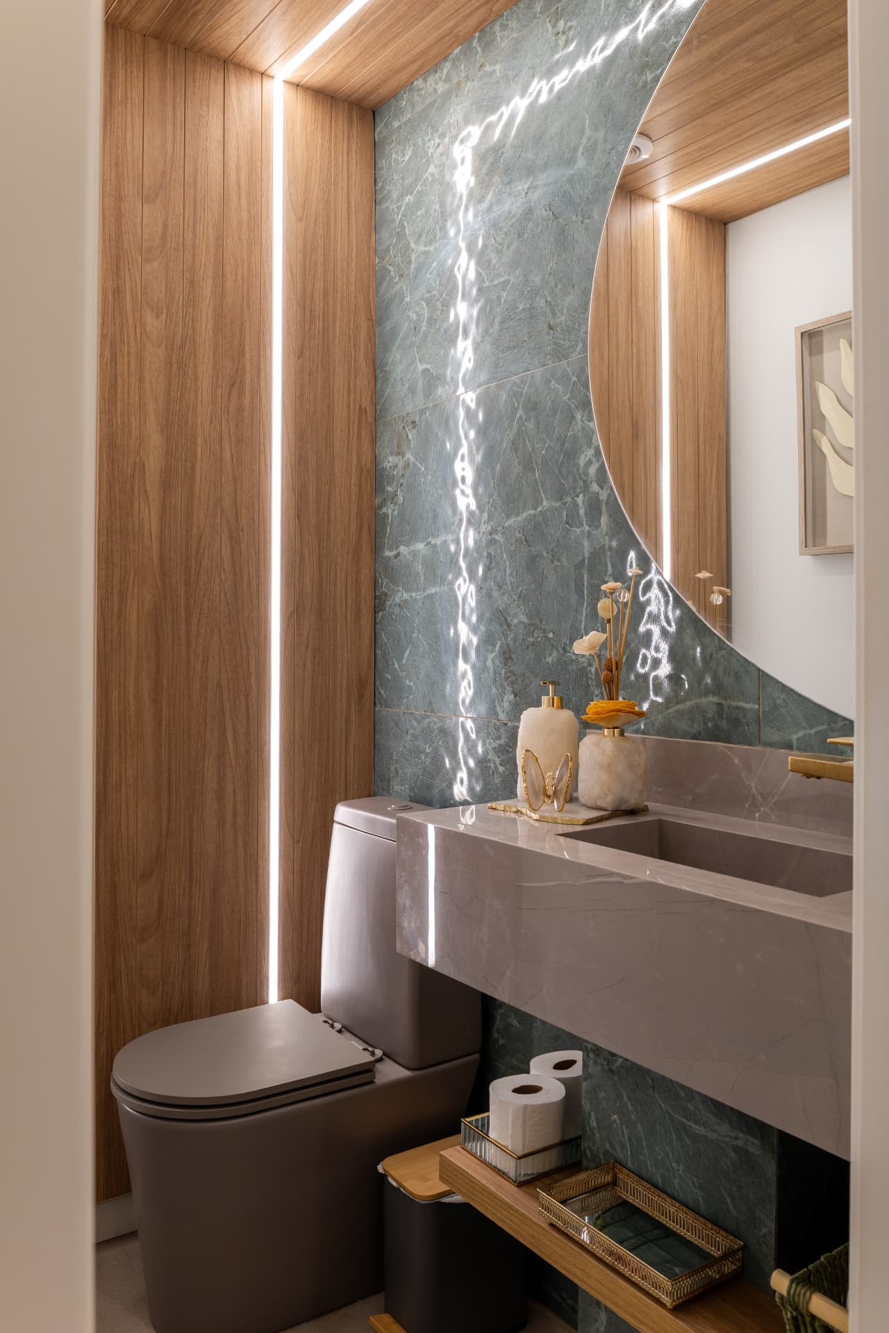 Lavabo sofisticado com marcenaria em madeira, mármore verde e iluminação de destaque